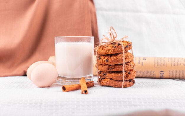 Ein Glas Milch mit Karamellkeksen, Zimtstangen und rohen Eiern