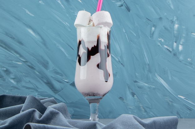 Kostenloses Foto ein glas milchshake neben dem handtuch auf dem blauen hintergrund. hochwertiges foto