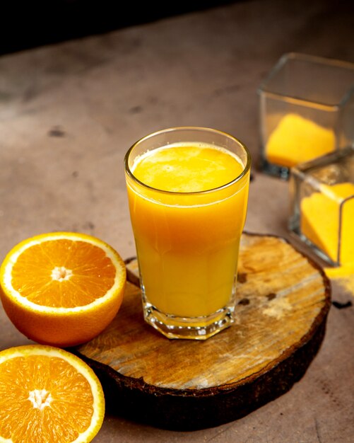 Ein Glas Orangensaft serviert auf Holzbrett