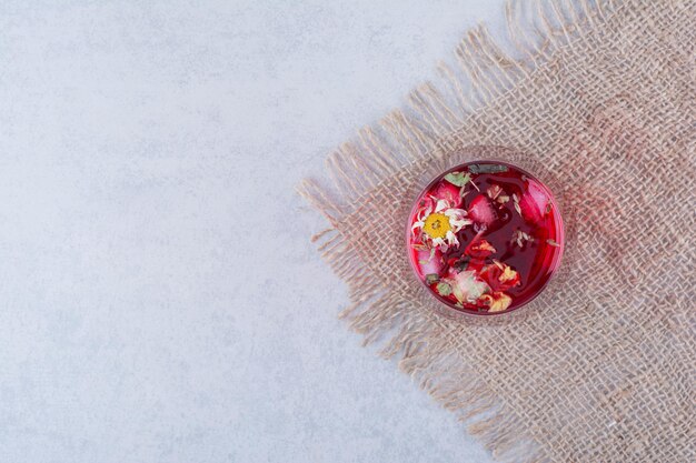 Ein Glas roter Saft auf Sackleinen mit Blumen.