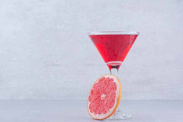 Ein Glas roter Saft mit Grapefruitscheibe auf Steinhintergrund. Foto in hoher Qualität