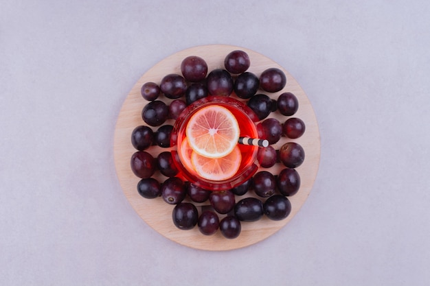 Ein glas roter saft mit kirschbeeren auf einem holzbrett