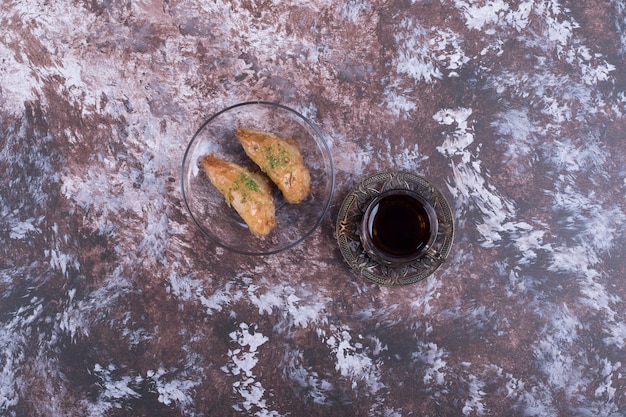 Ein Glas Tee mit türkischem Pakhlava in der Glasuntertasse in der Mitte.