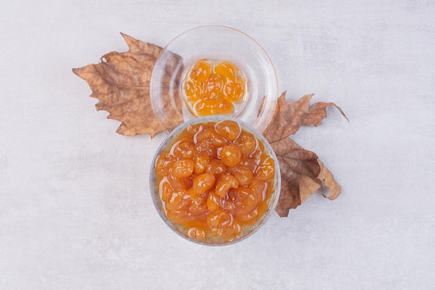 Kostenloses Foto ein glas teller mit marmelade und blatt auf weißem tisch.