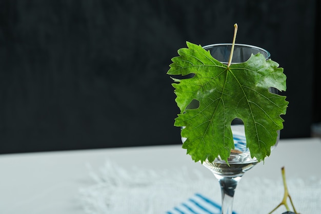 Ein Glas Wein mit Blatt auf weißem Tisch