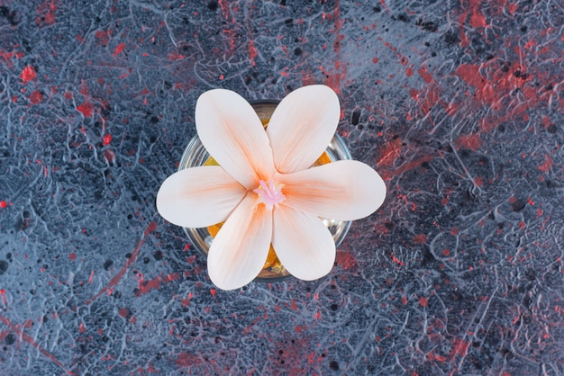 Ein Glasgefäß mit schöner rosa Blume auf Marmorhintergrund.