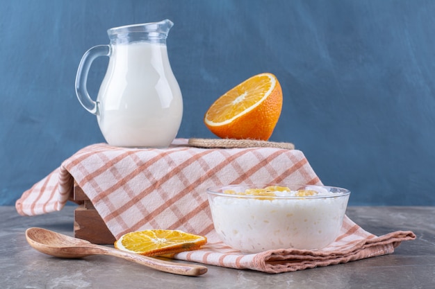 Ein Glaskrug Milch mit gesundem Haferbrei und geschnittenen Orangenfrüchten.