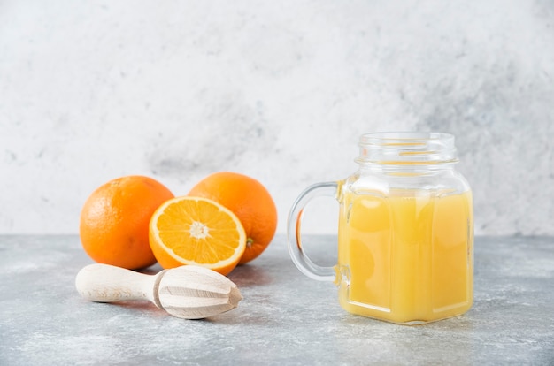 Kostenloses Foto ein glaskrug saft mit frischen orangenfrüchten auf steintisch.