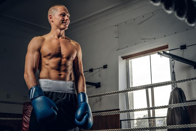 Ein glücklich lächelnder Mann steht nach dem Kickbox-Sparring auf dem Ring.