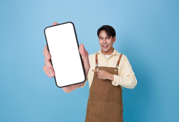 Ein glücklicher barista-asiatischer Mann zeigt ein Smartphone-Mockup und zeigt mit dem Finger einen leeren Bildschirm in einem Café