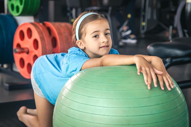 Ein glückliches Mädchen streckt sich im Fitnessstudio auf einem Fitball aus