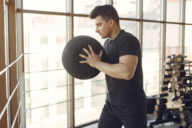 Ein gutaussehender mann ist in einem fitnessstudio beschäftigt