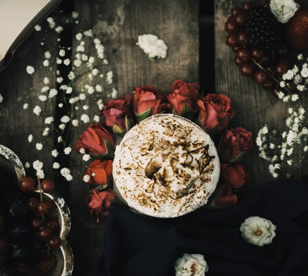 Ein heißer Kaffee der oberen Nahaufnahme, der auf den roten Rosen und der braunen rustikalen Holzoberfläche lecker schmeckt