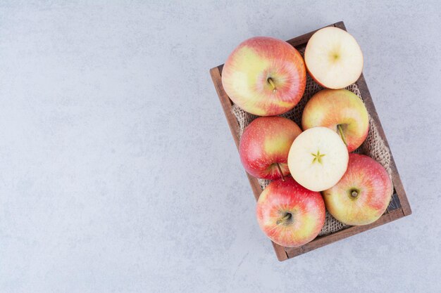 Ein hölzerner Korb voller Äpfel auf weißem Hintergrund. Foto in hoher Qualität