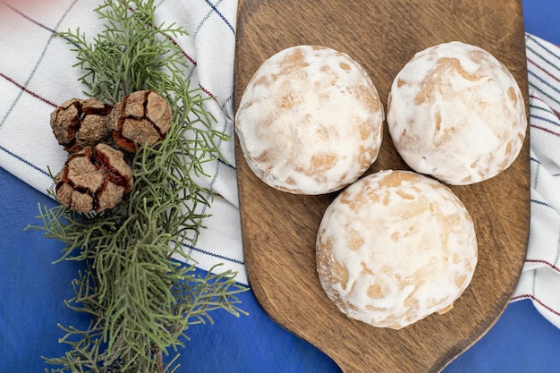 Kostenloses Foto ein hölzernes schneidebrett mit drei lebkuchen und tannenzapfen