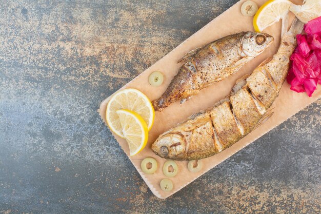 Ein Holzbrett aus geschnittenem Fisch mit Zitrone und Kohl. Foto in hoher Qualität