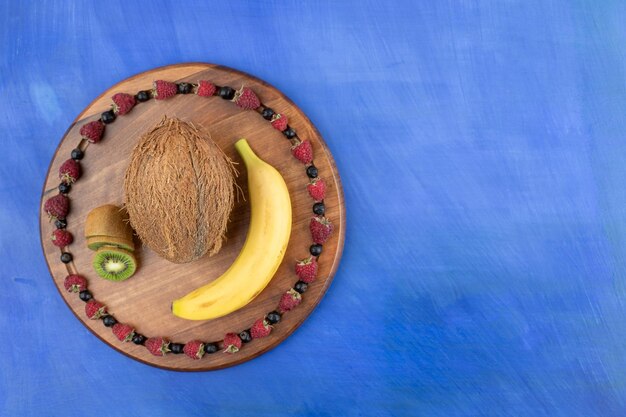 Ein Holzbrett aus Kokosnuss, Kiwi und Banane