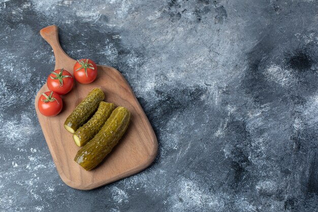 Ein Holzbrett aus Tomaten und eingelegten Gurken.