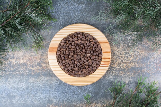 Ein Holzbrett mit Kaffeebohnen auf Marmorhintergrund. Foto in hoher Qualität