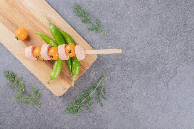 Ein Holzbrett mit kirschgelben Tomaten und Chilischoten.