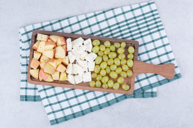 Ein Holzbrett voller Weißkäse und geschnittenen Früchten. Foto in hoher Qualität