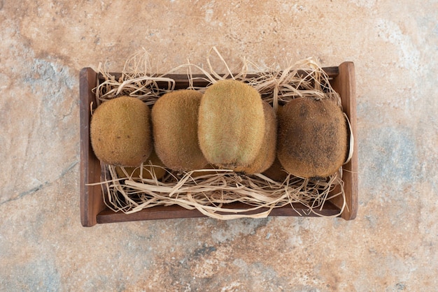 Ein Holzkorb mit frischer Kiwi auf Marmor