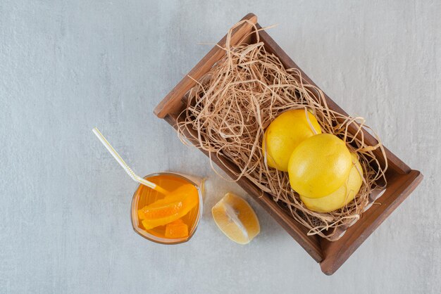 Ein Holzkorb mit Zitronen und einem Glas Saft