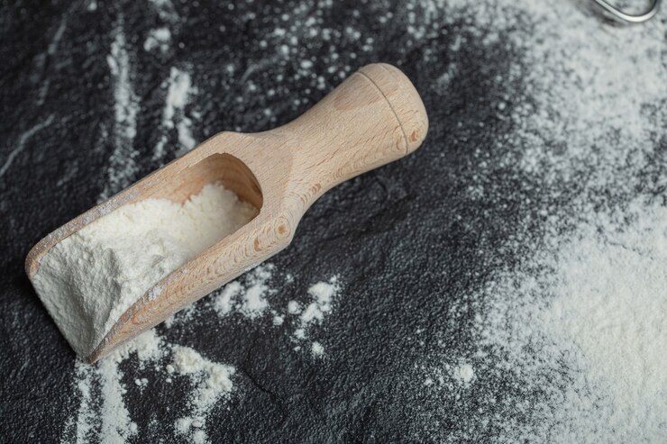 Kostenlose Foto ein holzlöffel mit mehl auf schwarz.