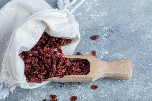 Ein Holzlöffel voller getrockneter Preiselbeeren auf Marmoroberfläche.