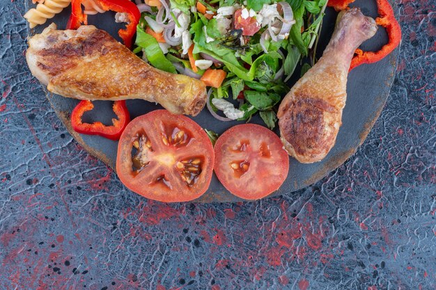 Ein Holzstück gebratenes Hühnerbeinfleisch mit Gemüsesalat.