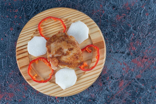 Ein Holzteller mit Hähnchenschnitzel mit geschnittenem Pfeffer.