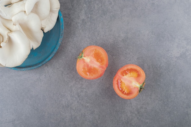Ein holzteller mit pilzen und tomatenscheiben