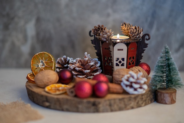 Ein Holzteller voller getrockneter Orangen und roter kleiner Weihnachtskugeln. Hochwertiges Foto