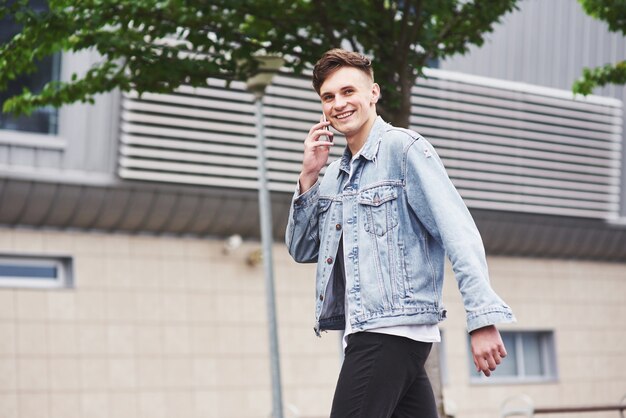 Ein hübscher junger Mann, der am Telefon nahe dem Büroraum spricht.