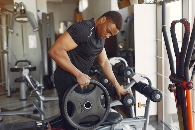 Ein hübscher schwarzer mann ist in einem fitnessstudio beschäftigt