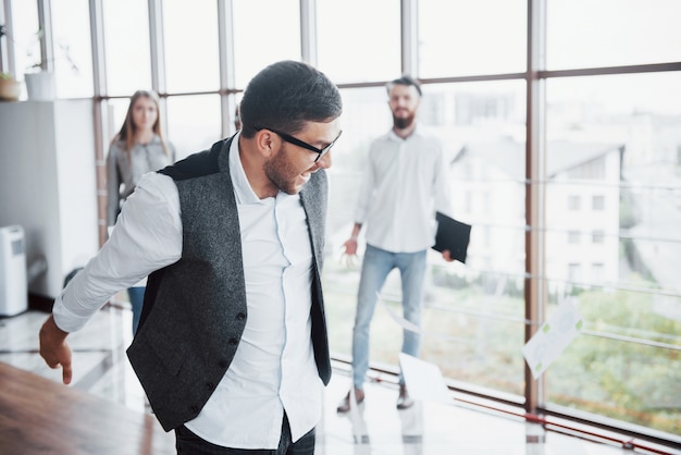 Ein hübsches Team junger Arbeiter im Büro, die Dokumente über die Freude an der Unterzeichnung des Falls werfen.