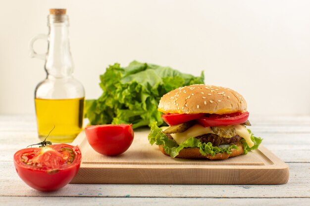 Ein Hühnchen-Burger mit Käse und grünem Salat und Olivenöl von vorne auf dem Holzschreibtisch und Sandwich-Fastfood