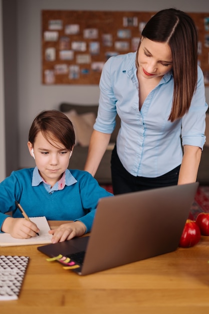 Ein jugendlicher Junge telefoniert mit einem Laptop mit seinem Lehrer neben seiner Mutter über einen Laptop