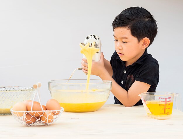Ein Junge macht Kuchen. Foto ist auf sein Gesicht gerichtet.