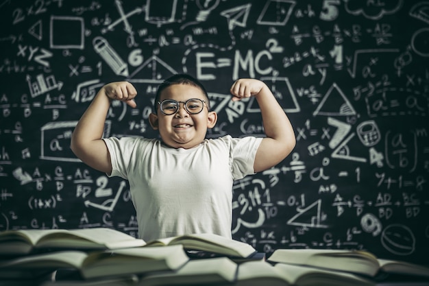 Ein Junge mit Brille sitzt im Arbeitszimmer und mit beiden Armen senkrecht