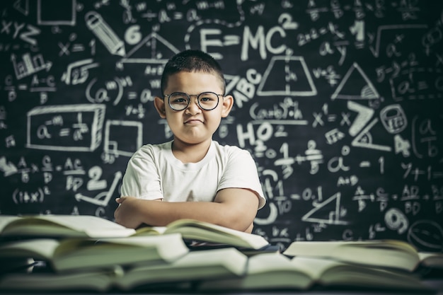 Ein junge mit brille sitzt im klassenzimmer und liest