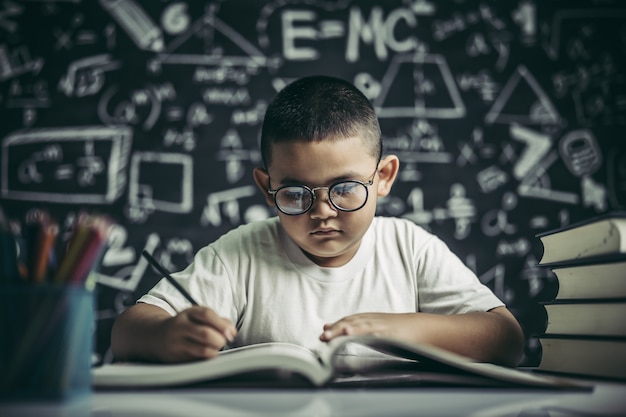 Ein Junge mit Brillenmann, der im Klassenzimmer schreibt