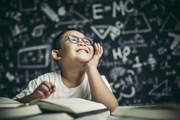 Kostenloses Foto ein junge mit brillenmann, der im klassenzimmer schreibt