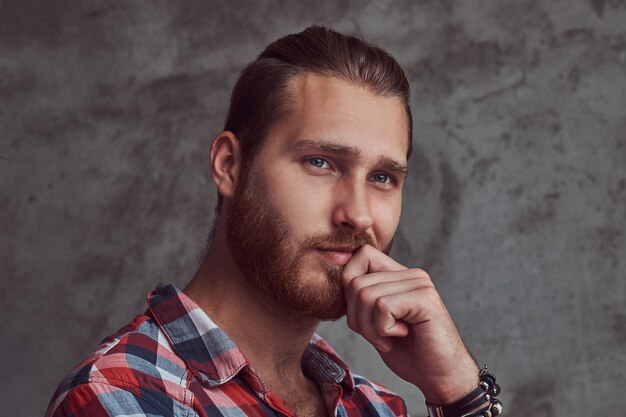 Ein junger hübscher rothaariger vorbildlicher Mann in einem Flanellhemd auf einem grauen Hintergrund.