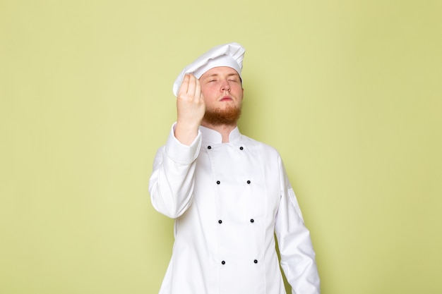 Ein junger männlicher Koch der Vorderansicht im weißen Kochkappen-Weißkopfkappen-Geschmackszeichen