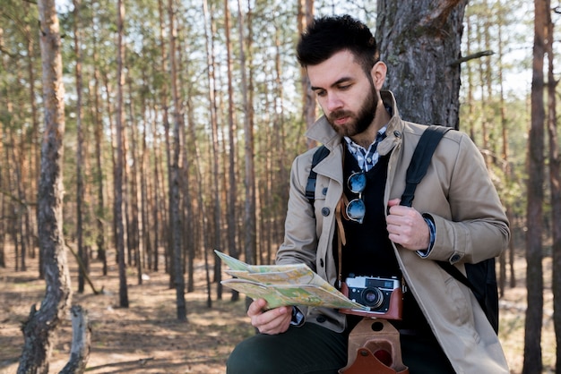 Ein junger männlicher Tourist, der die Karte im Wald liest