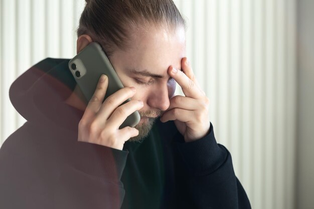 Ein junger Mann, der auf dem Smartphone spricht und sein Kopfkonzept des Problems hält