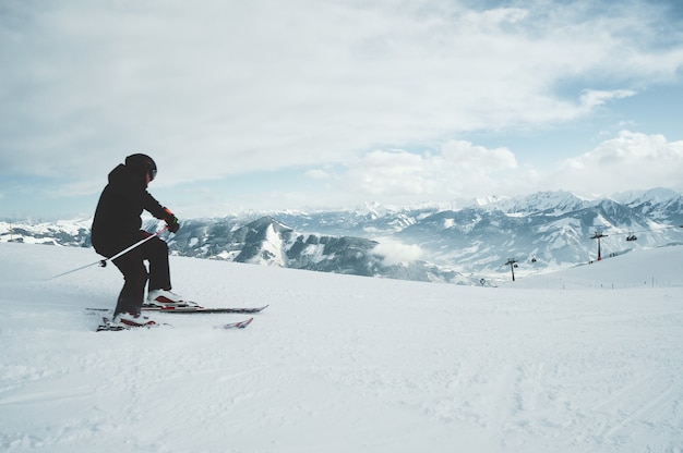 Ein junger Mann, der auf den im Schnee bedeckten Bergen Ski fährt