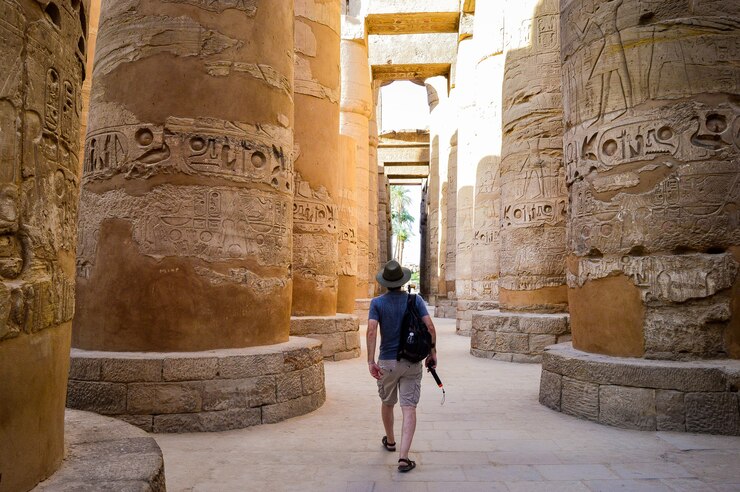 Kostenlose Foto ein junger mann, der in einem ägyptischen tempel spazieren geht