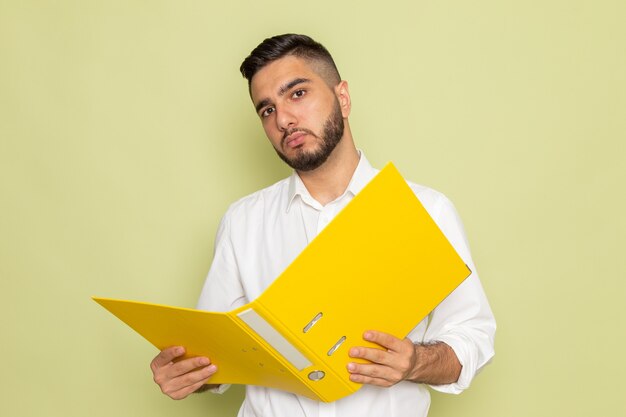 Ein junger Mann der Vorderansicht im weißen Hemd, das gelbe Dateien hält
